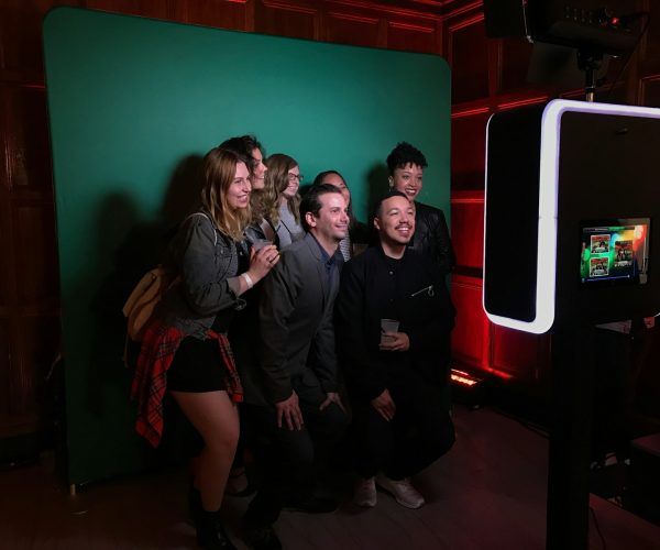 A group of people standing in front of a green screen